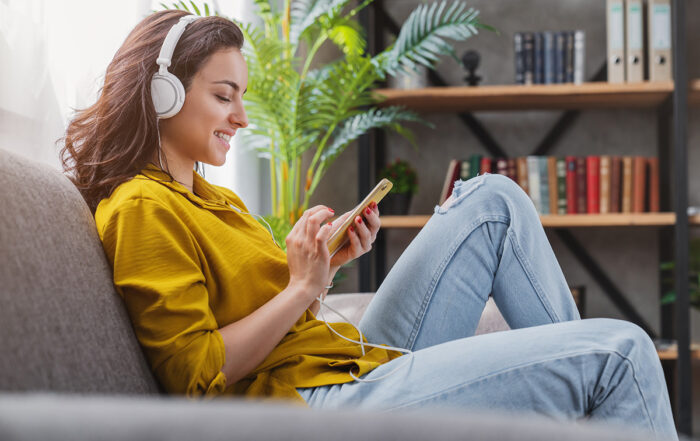 Happy young woman relaxing and listening to music using her smartphone